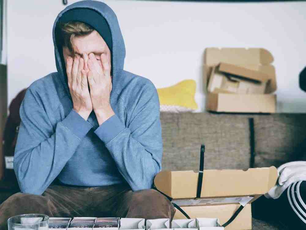 男人坐在长凳上用双手捂住脸